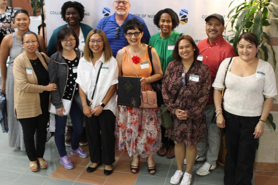 A group of nursing alumni gather together for a group photo at homecoming.