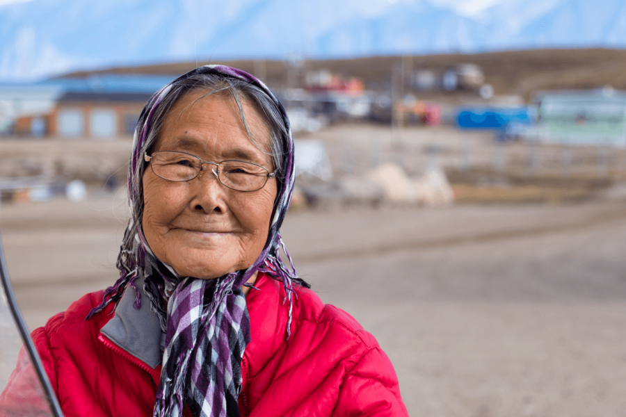 An elderly Inuit woman smiling at the camera.