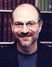 Photo de Harvey Chochinov, barbe et cheveux gris.  Il porte des lunettes et un blazer foncé.   Placé devant une bibliothèque, il sourit.