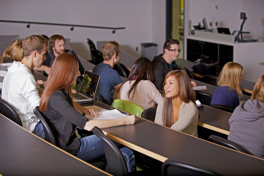 A group of pharmacy students seated at rows of tables in a lecture theatre. 