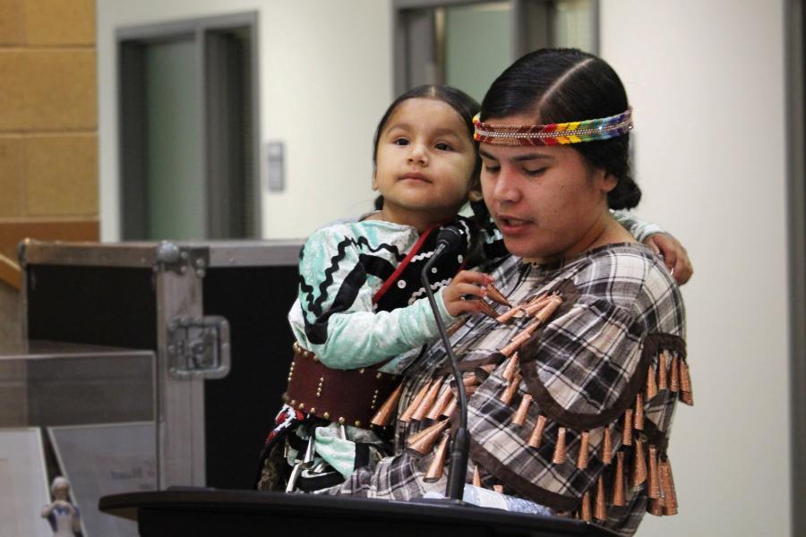 A woman in traditional Indigenous dress holding a toddler.