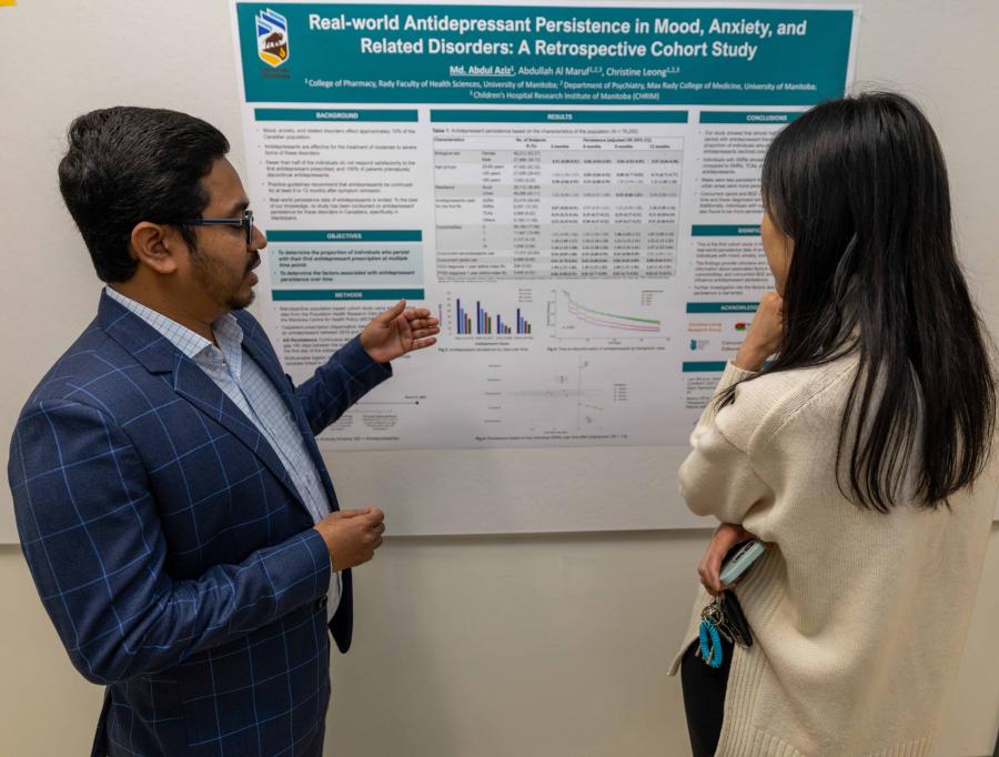 a pharmacy grad student explains their research to a person who is viewing the student's research poster.