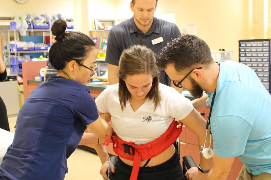 Students work together to assist a patient with mobility issues.