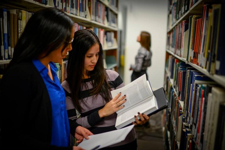 Students read a textbook together in the library.