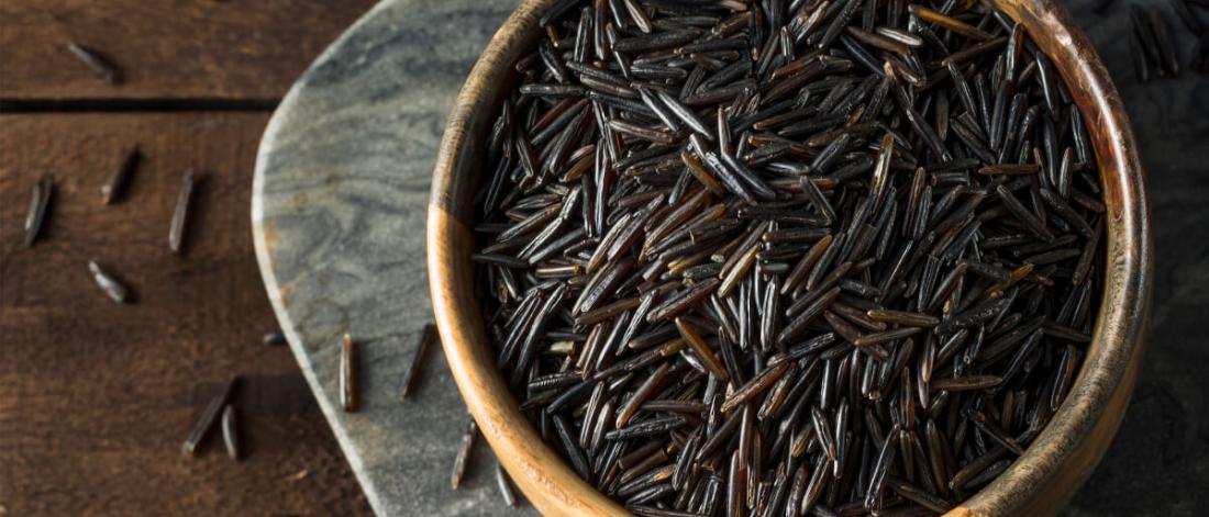 A bowl filled with grains of brown wild rice.