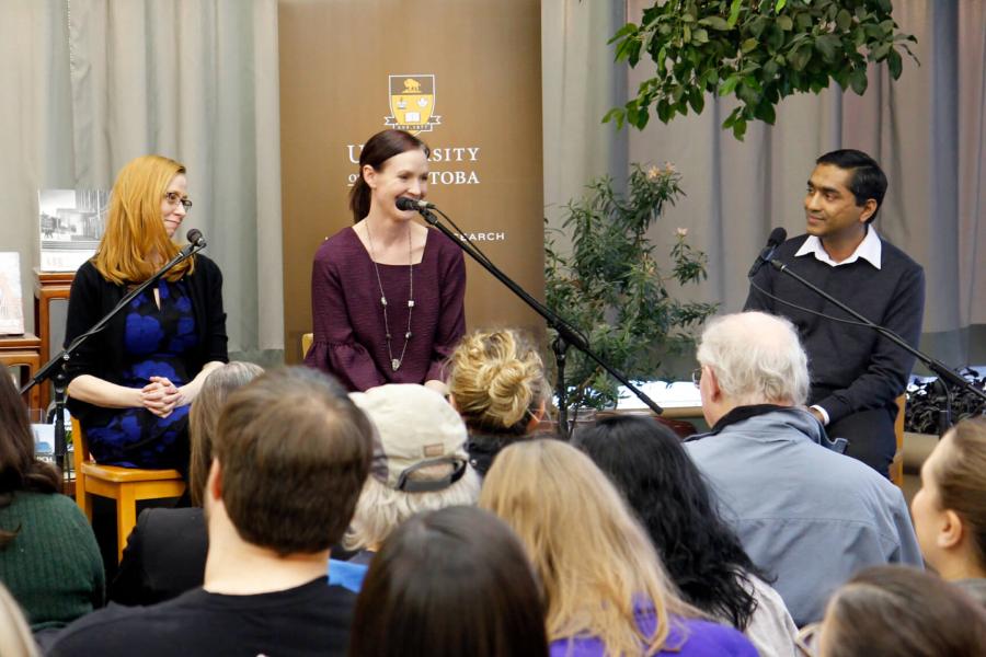 Four Cafe Scientifique panelists sit side by side on stage talking to a crowd of attendees. 