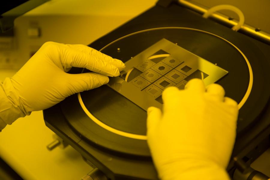 a pair of gloved hands carefully work with a piece of laboratory equipment. 