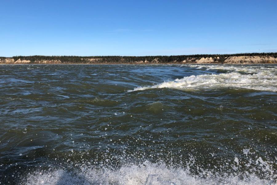 A rapidly moving body of water with a visible shoreline in the distance.