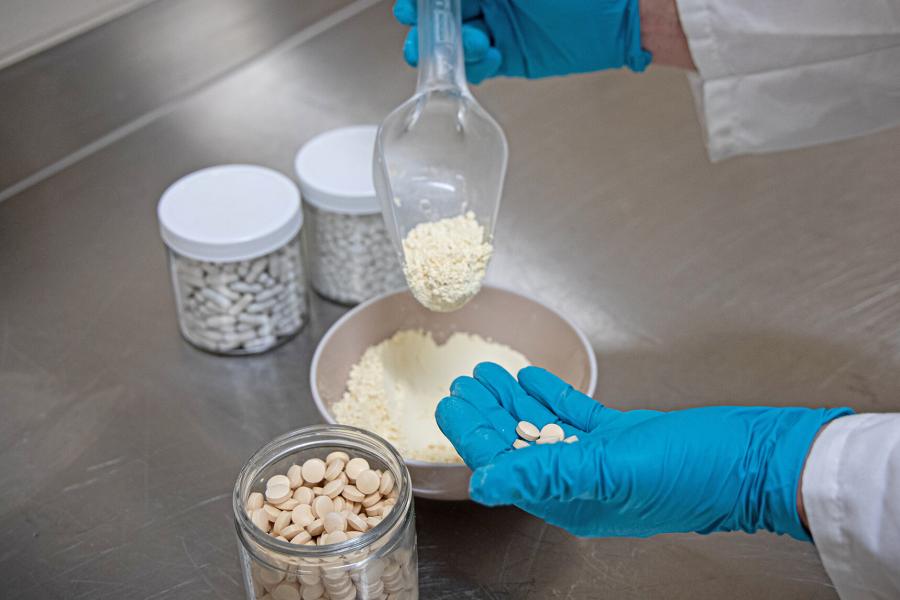 Jars of pills, a bowl of powder and hands holding tablets.
