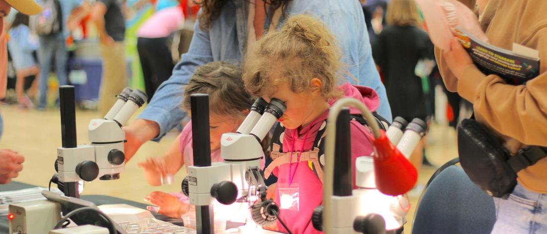 A little girl looking through a microscope.