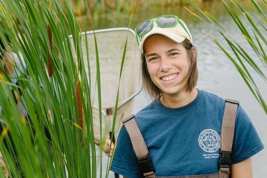 Jillian Detwiler smiling at the camera with water and prairie grass in the background.