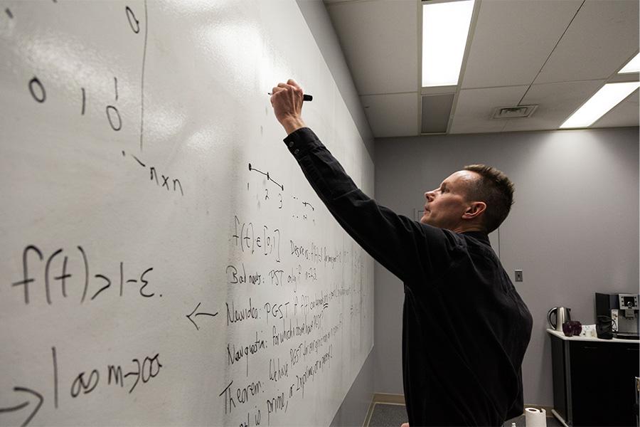 Stephen Kirkland writing a mathematical equation on a white board.