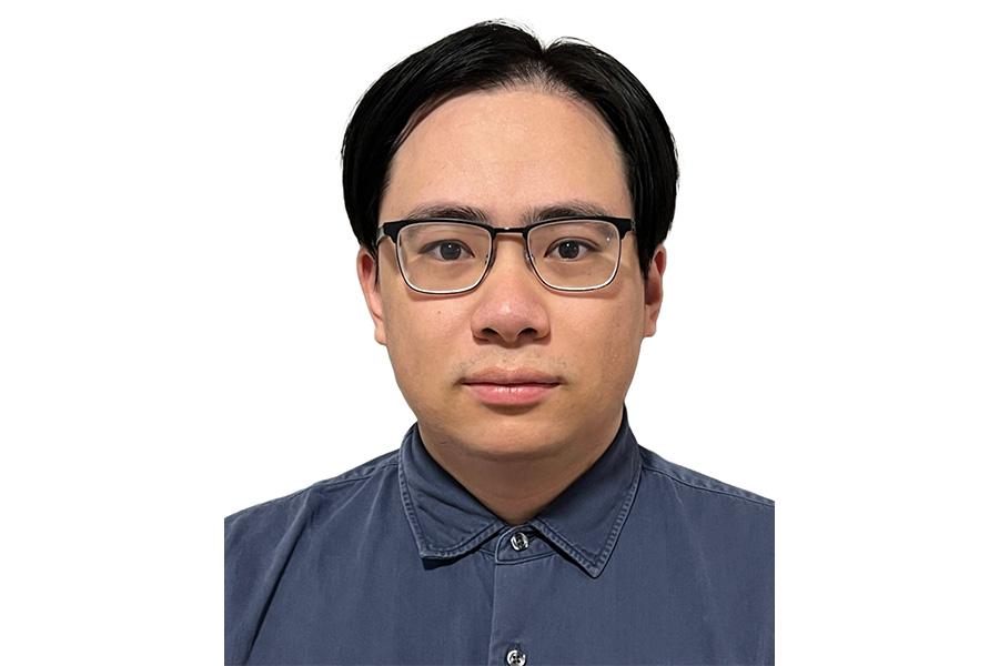 Chengzhou Tang wearing an eyeglass and looking at the camera.