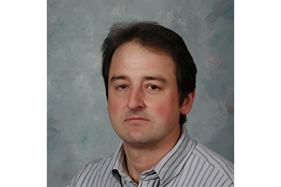 Kirill Kopotun wearing a striped collar shirt and smiling at the camera.