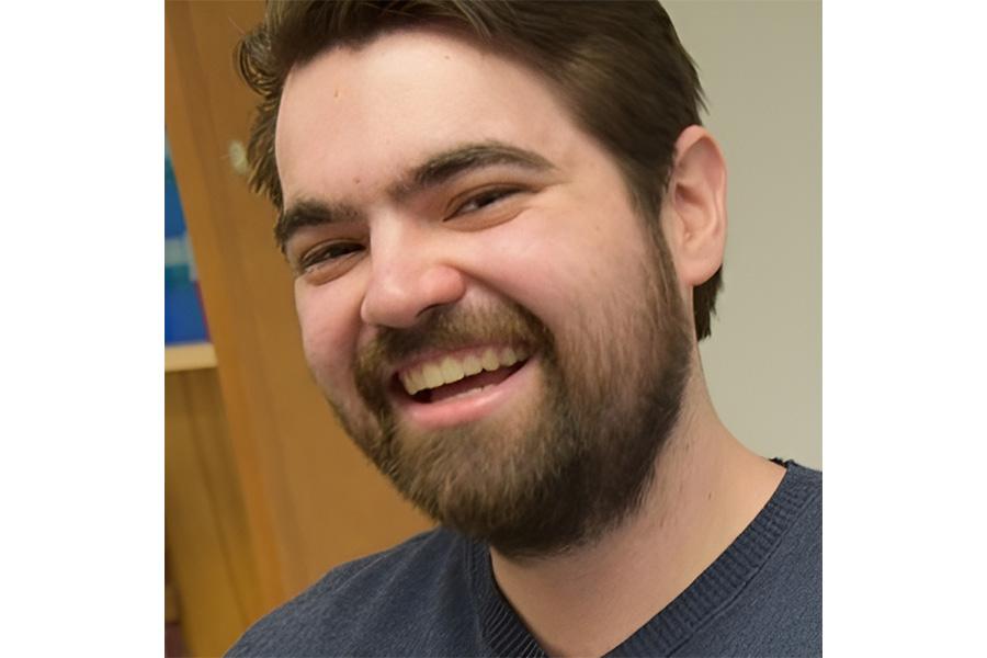 Michael Becker wearing a gray shirt and smiling at the camera.