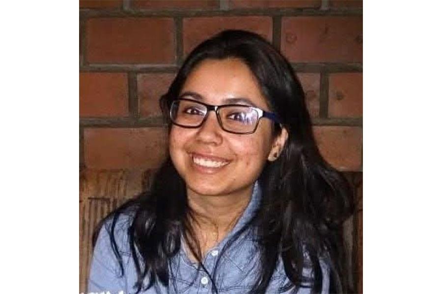 Debomita Bhattachary wearing a blue button down shirt and eyeglasses smiling at the camera.