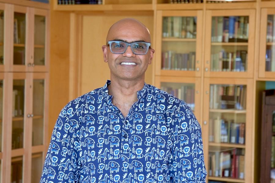 Abishek wearing a printed button down shirt and eyeglass smiling at the camera.