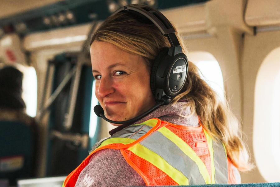 Courtney Shuert wearing a safety vest and a headphone smiling at the camera.