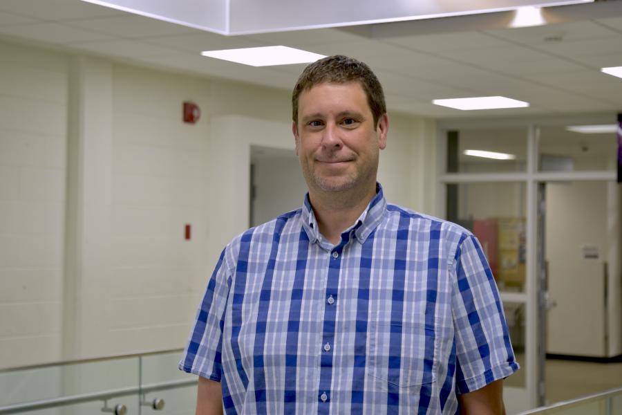 Ryan Mckenzie wearing a blue patterned button down shirt smiling at the camera.