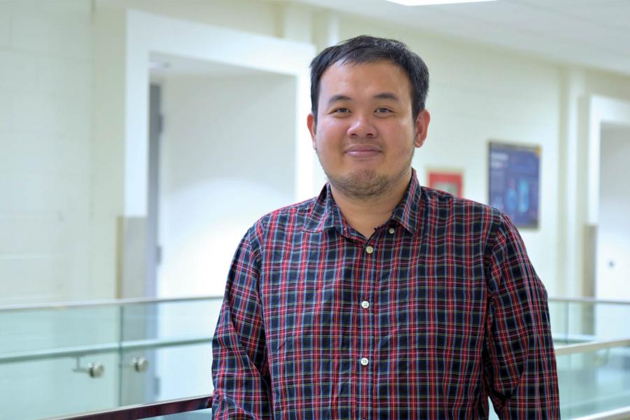 Trung Chau wearing a plaid button down long sleeves smiling at the camera.