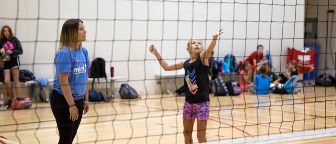 A junior volleyball player serves the ball.