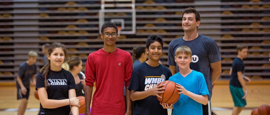 A group of young basketballers poses in the gym with their Mini U leader. 