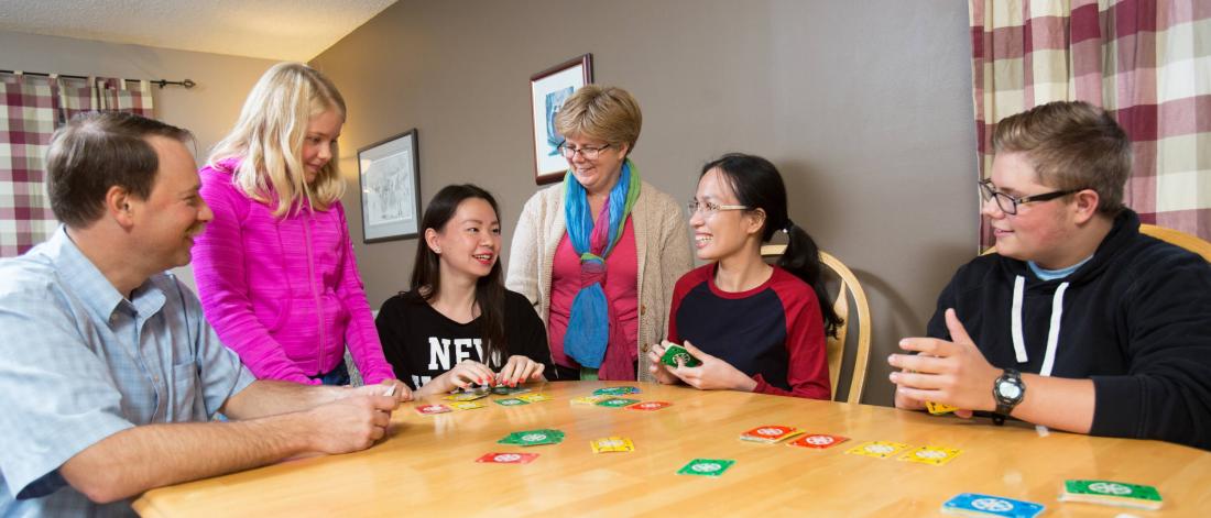 A homestay host family and student play a card game together. 