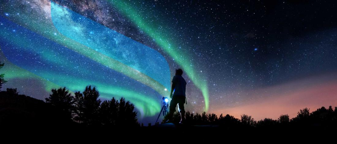 A silhouette of a photographer in front of a night sky that has stars and the northern lights overlaid with U M branding. 