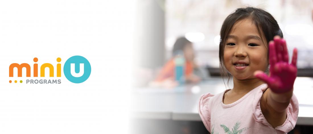 A young girl holds her hand toward the camera with her palm painted pink.