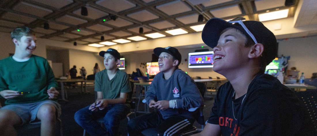 A group of boys smiling while playing a video game