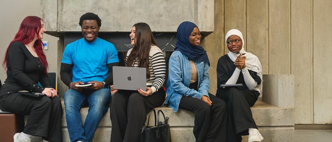 A group of students sit and smile together.