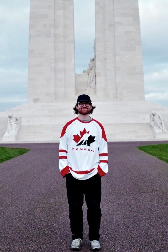 Jayden, standing in front of a tall structure and smiling on camera.