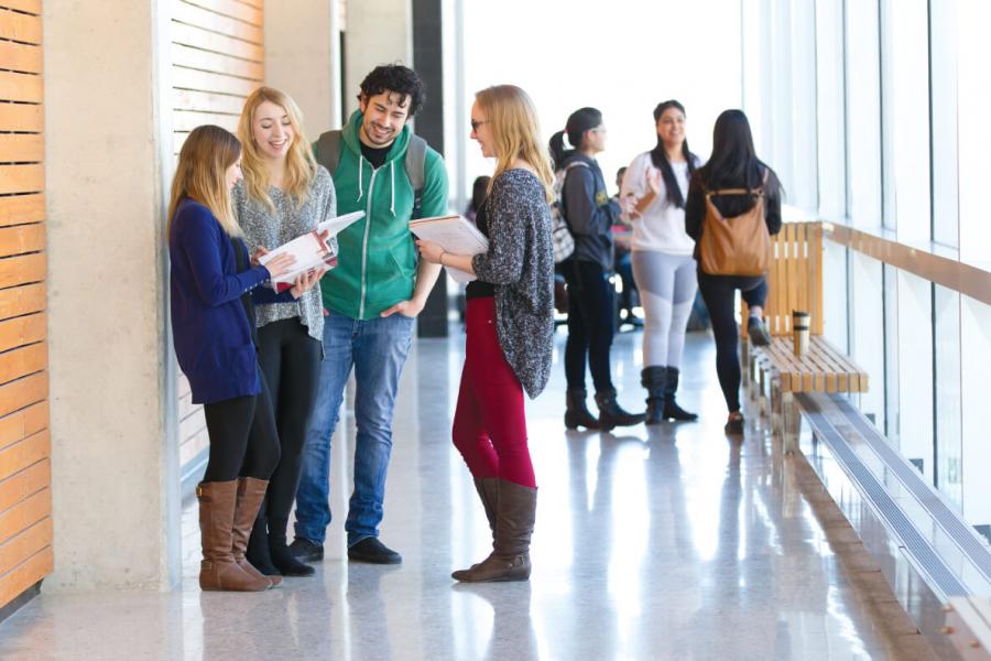 Undergraduate students chatting in the hall at the University of Manitoba.