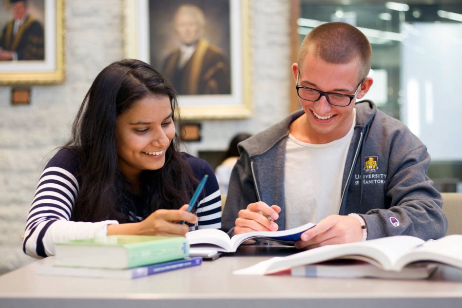 One University of Manitoba student happily tutoring another student in an on campus library.