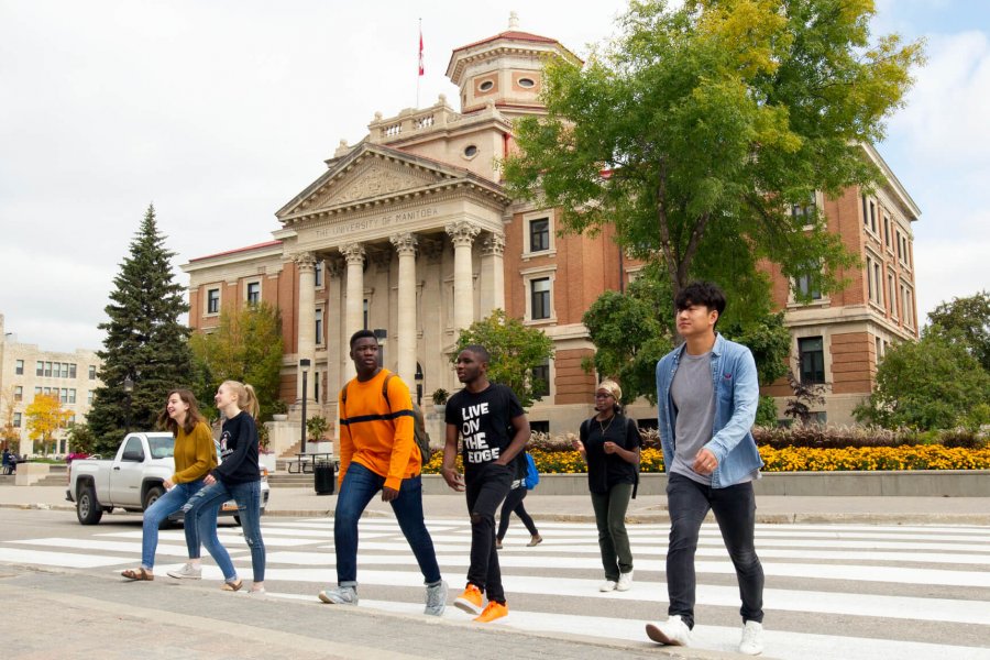 A group of University of Manitoba students walking across the street in front of the Administration building.