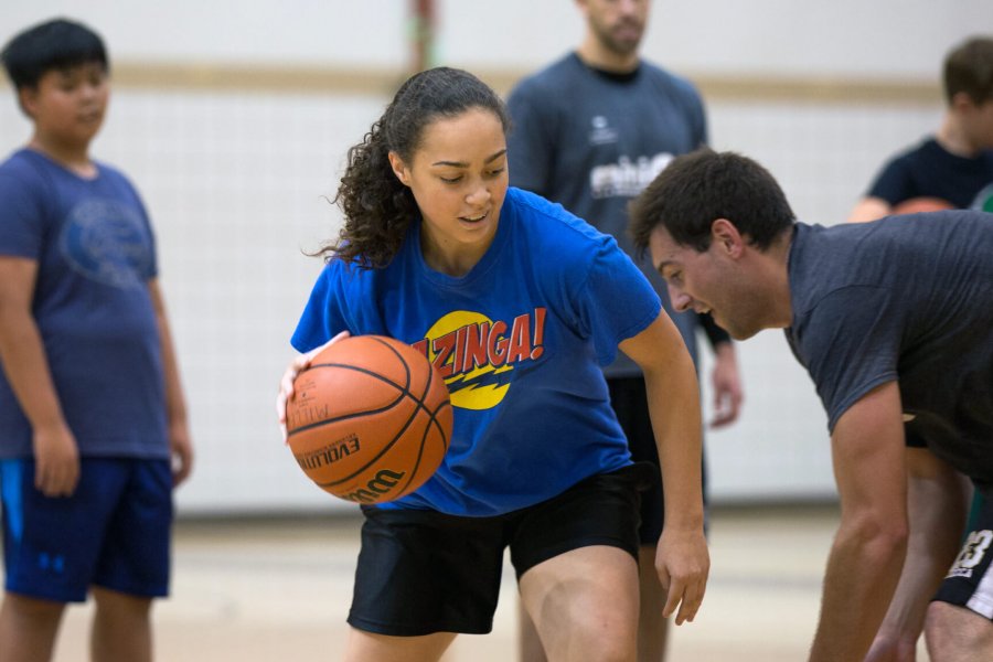 A junior program participant dribbles a basketball attempting to get past her opponent.