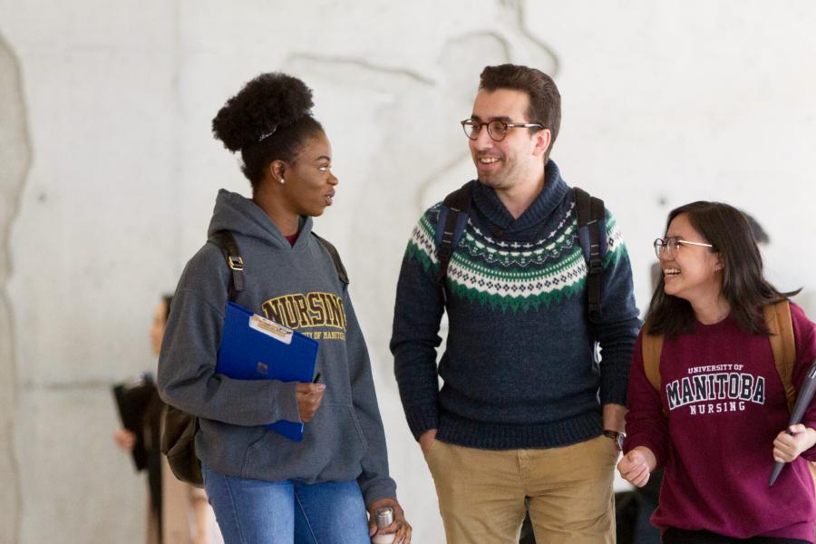Three students walking together exchanging conversation and laughter.