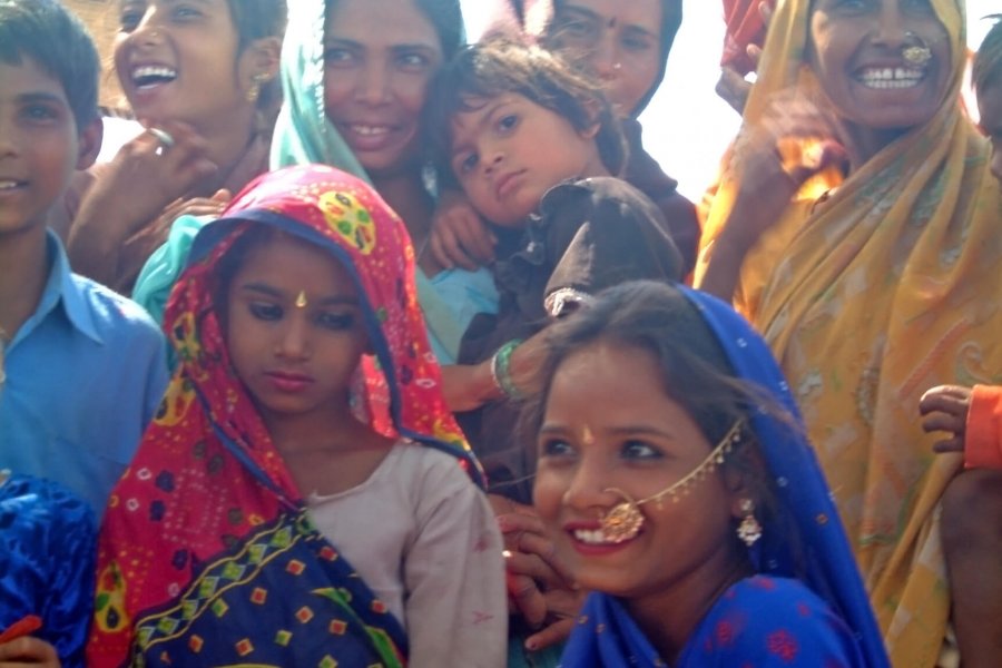 Colourfully dressed, smiling women and children from a community in India.