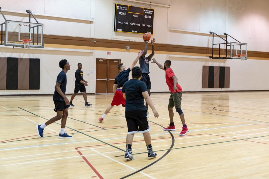 A group of 6 students playing a recreational basketball game on the Frank Kennedy Centre gymnasium basketball court.