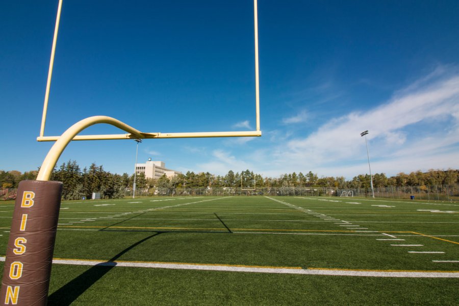 A view of the football sports field from the end zone goal posts.