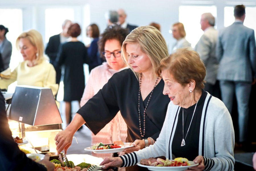 People help themselves to some food at a buffet line during an event. 