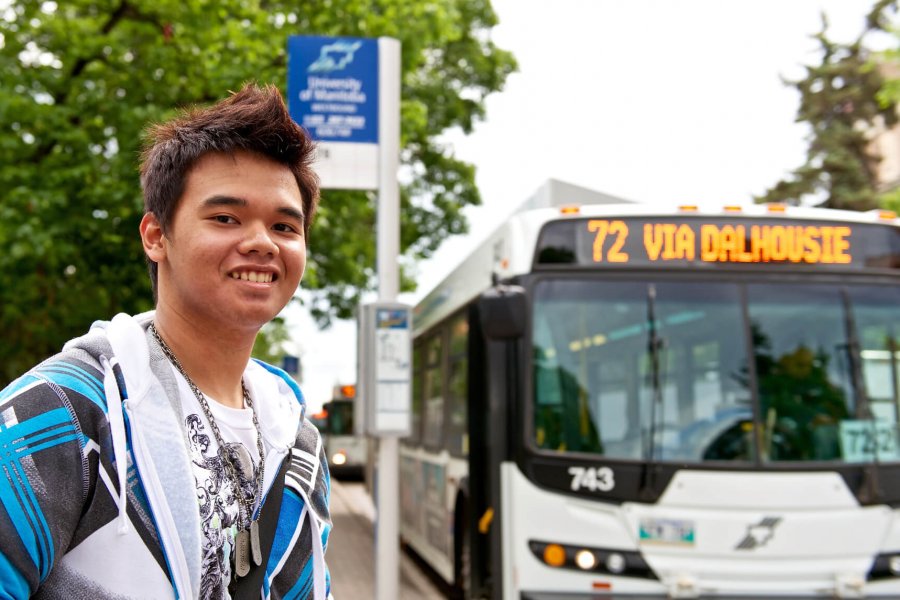 A University of Manitoba student stands at the bus stop waiting for the bus.