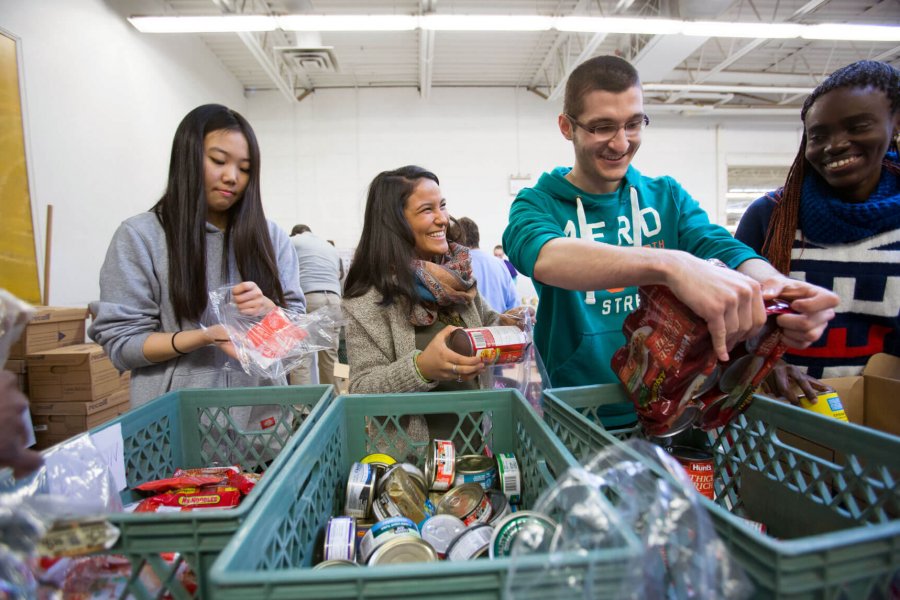 Four students pack non-perishable food items into bags at Winnipeg Harvest. 