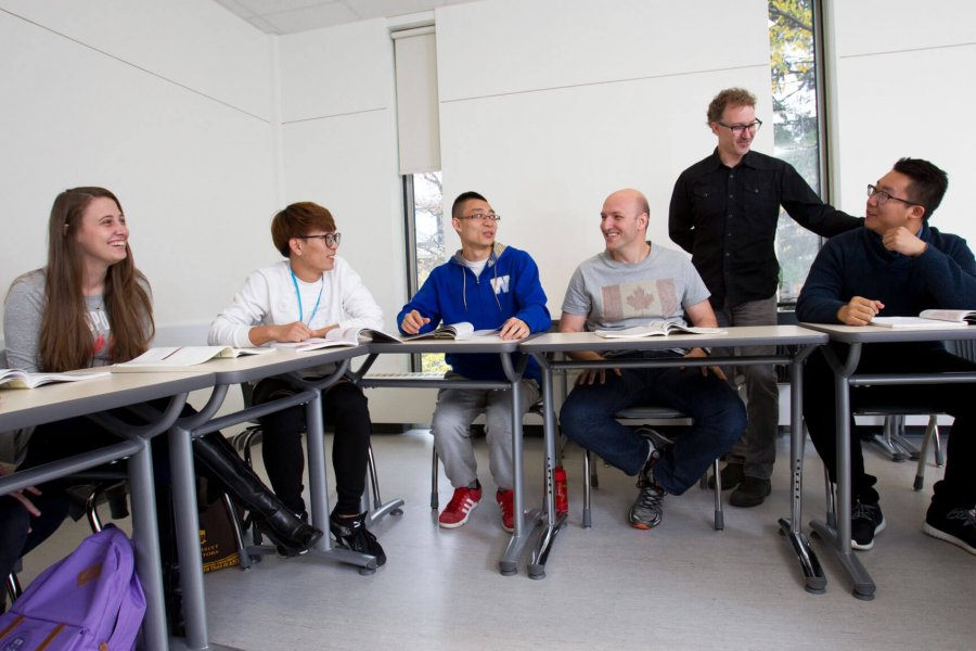 A classroom of smiling students listening to their instructor. 