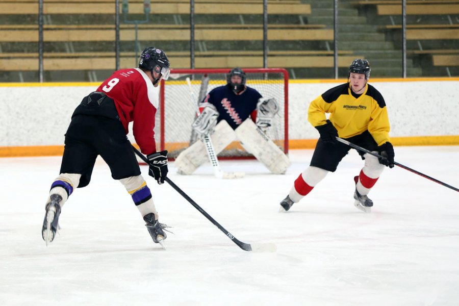Three young adults playing a casual game of hockey.