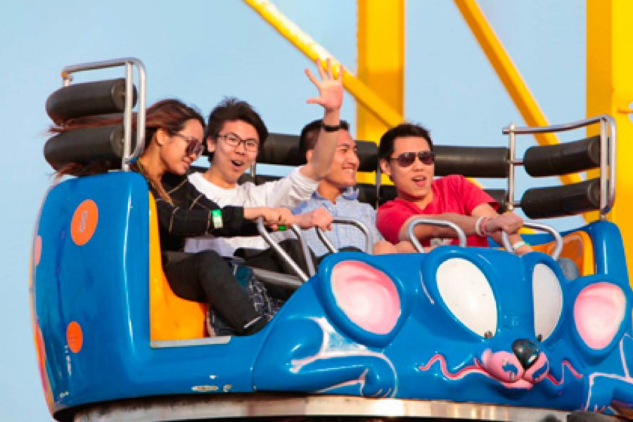 Four students smiling as they enjoy a carnival ride.