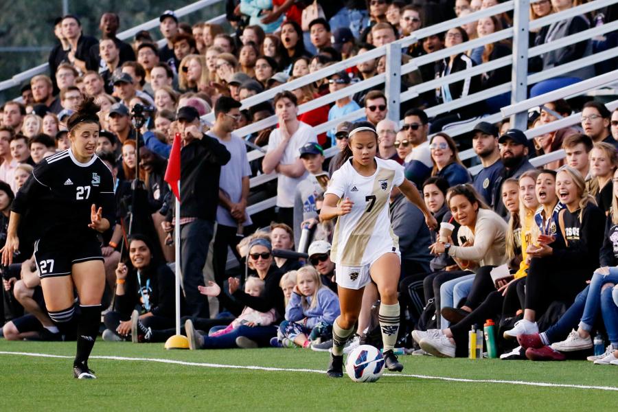 An image of student playing a soccer game by kicking a ball and running.