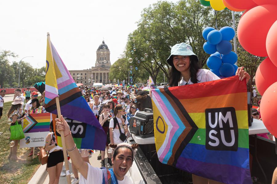 student pictured outdoors holding pride flag with umsu