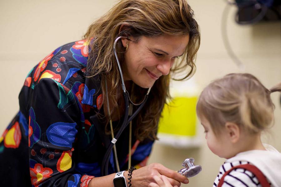 A doctor examines a small child with a stethoscope.