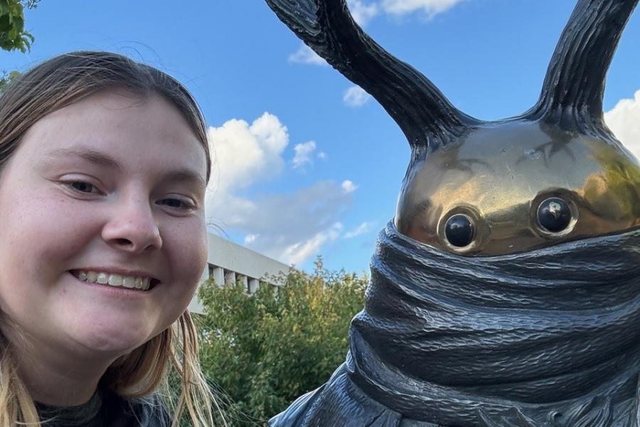 Exchange student Madi poses with a sculpture on UM's campus.